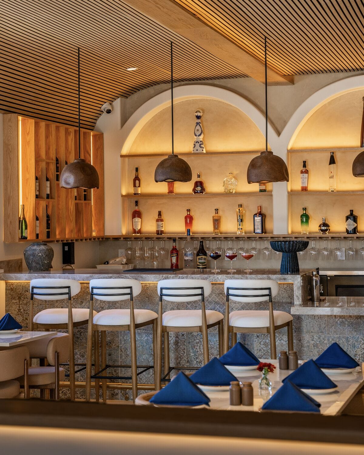 Arched bar with bar stools and set dining tables in Manhattan Beach