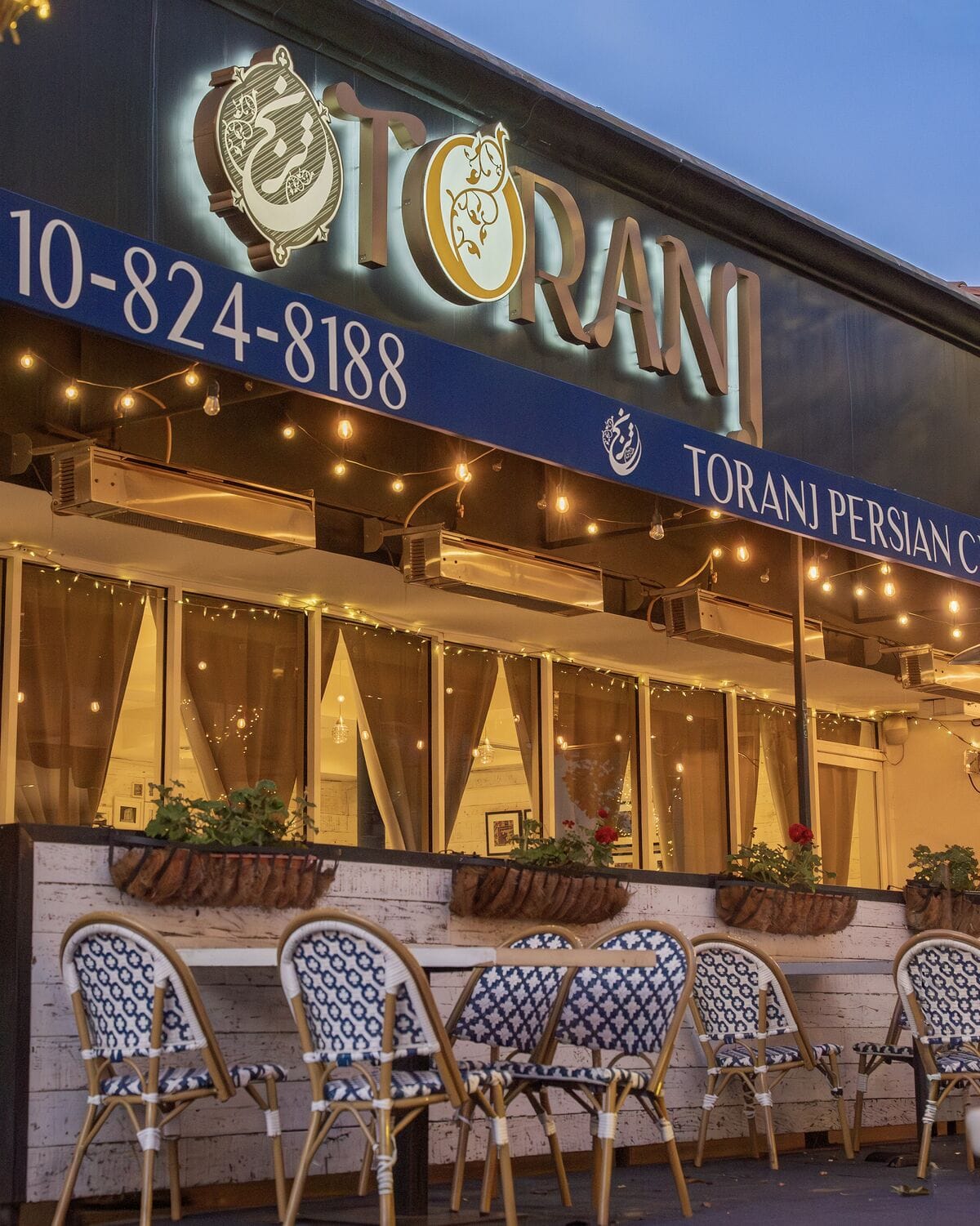 Lit Toranj storefront and sidewalk seating in Westwood Village at dusk in Westwood Village